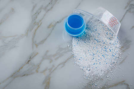 Laundry detergent powder and blue liquid gel in measuring cupの写真素材