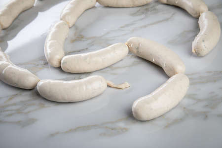 Raw German Bavarian Weißwurst white sausage chain on marble backgroundの写真素材