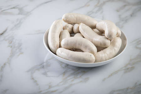 Raw German Bavarian WeiÃwurst white sausage chain on plate and marble backgroundの写真素材