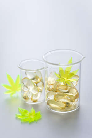 Pills, tablets,  capsules of cannabis marijuana hemp and CBD in lab scale glass beaker as pain killer and medicalの写真素材