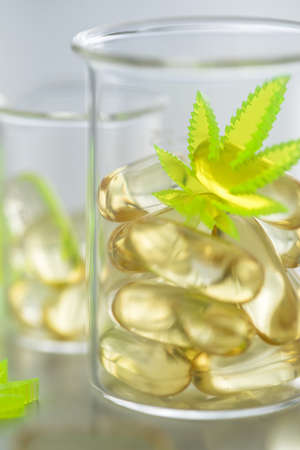 Pills, tablets,  capsules of cannabis marijuana hemp and CBD in lab scale glass beaker as pain...