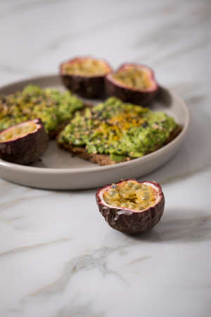 Avocado and turmeric on sunflower seed whole grain bread slice with passion fruit for breakfast or...