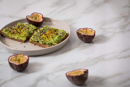 Avocado and turmeric on sunflower seed whole grain bread slice with passion fruit for breakfast or...