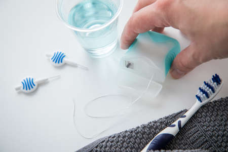 Woman using toothbrush, mouthwash, floss and blue interdental brushes as equipment for daily dental...
