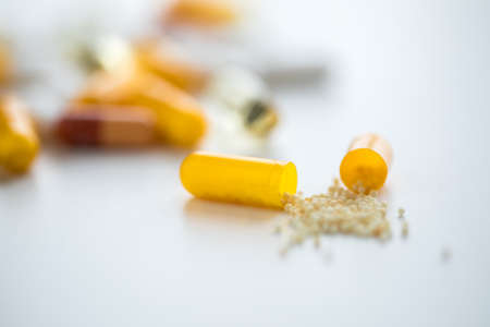 White and yellow pills, tablets and capsule medicine on white backgroundの写真素材