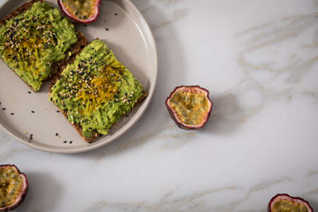 Avocado and turmeric on sunflower seed whole grain bread slice with passion fruit for breakfast or...