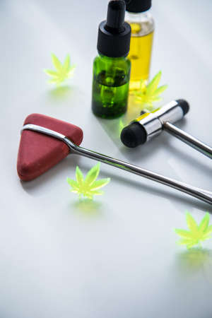 Cannabis marijuana hemp CBD oil as pain killer or medical therapy for multiple scleroses, Parkinson, depression, spasticity at neurologist doctors office with reflex hammerの写真素材
