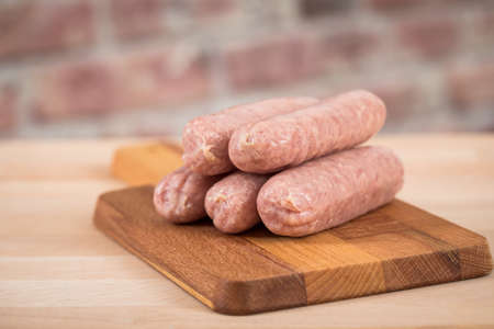 Raw fresh coarse sausages in domestic kitchen on wooden boardの写真素材