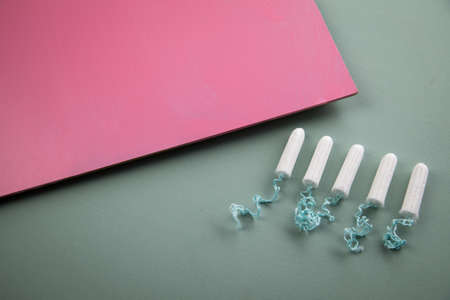 Tampons on green mint and rose pink background for female personal hygiene and protection during...
