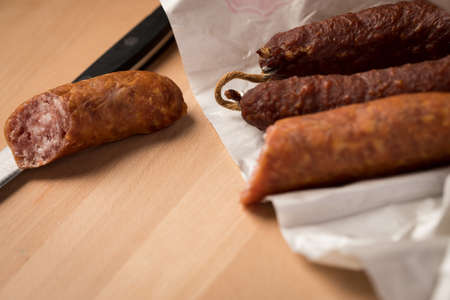 Ring Salami pork sausage with German BierbeiÃer in wax paper with knife on wooden board background for Brotzeit dinnerの写真素材