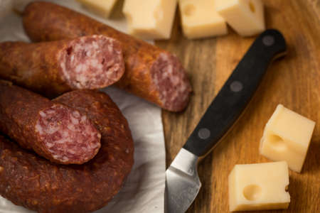 Ring salami pork sausage with German beer and cheese Edam cheese in wax paper on wooden board background for lunch timeの写真素材