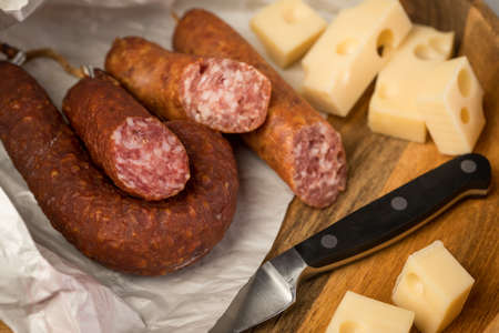 Ring salami pork sausage with German beer and cheese Edam cheese in wax paper on wooden board background for lunch timeの写真素材