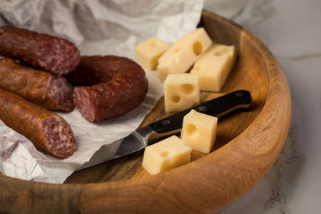 Ring salami pork sausage with German beer and cheese Edam cheese in wax paper on wooden board background for lunch timeの写真素材