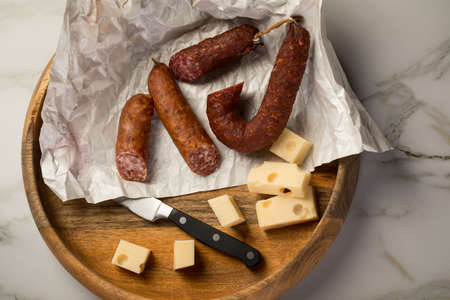 Ring salami pork sausage with German beer and cheese Edam cheese in wax paper on wooden board background for lunch timeの写真素材