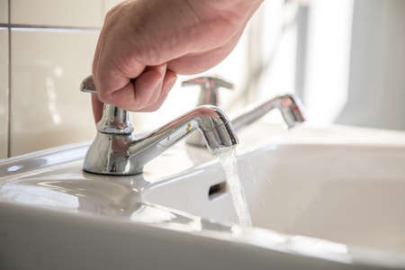 Man using washbasin with tap water for washing handsの写真素材