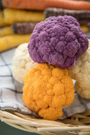 Colorful rainbow cauliflower in purple, orange and white on kitchen towel with knife in basket on pastel mint green backgroundの写真素材