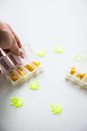 Woman taking pills, tablets of cannabis marijuana hemp and CBD as pain killer and medical therapy in box dispenserの写真素材