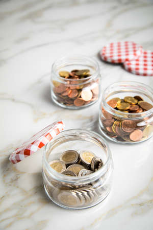 3 glass jars of loose cash and 2€ coins for housekeeping money, vacation or saving goals