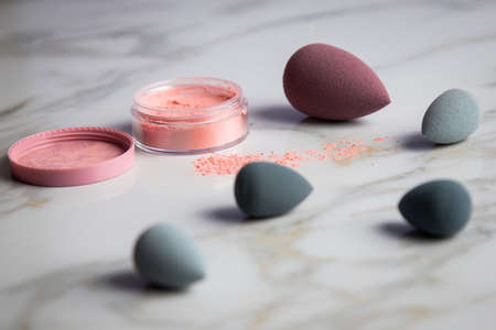 Loose rouge make-up powder with blender sponge on marble beauty tableの写真素材