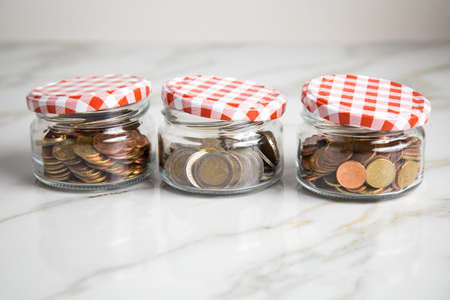 3 glass jars of loose cash and 2â¬ coins for housekeeping money, vacation or saving goalsの写真素材
