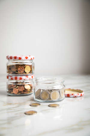 3 glass jars of loose cash and 2â¬ coins for housekeeping money, vacation or saving goalsの写真素材
