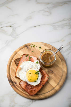 Roasted Bavarian Leberkaese meat loaf with fried egg on sunflower seed bread with sweet mustard on...