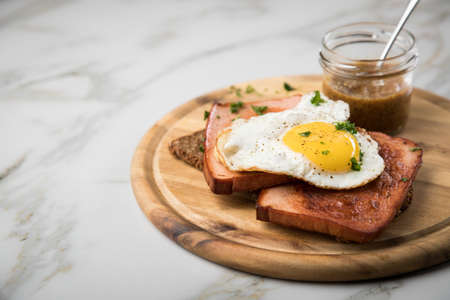 Roasted Bavarian Leberkaese meat loaf with fried egg on sunflower seed bread with sweet mustard on...