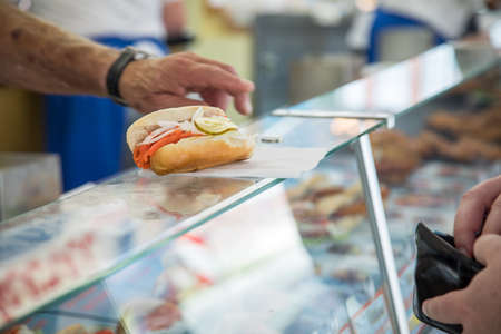 Man buying typical North German Friesland cuisine is Alaska Pollack bun with onions and pickled cucumber gherkin during fish market as fast regional snackの写真素材