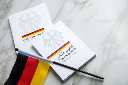 Passport and  constitution basic law book of Germany in German and Arabic language on flag and...