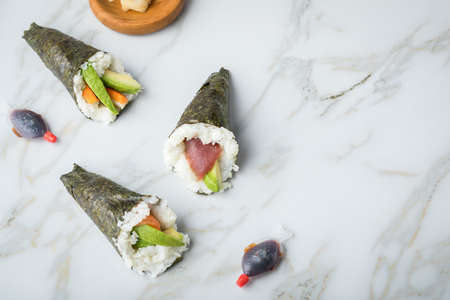 Salmon, tuna and Surimi avocado Temaki sushi with soy sauce fish, pickled ginger and wasabi on marble backgroundの写真素材