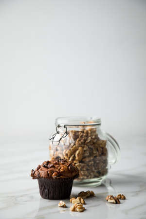 Walnut muffin and nuts in mason jar on light marble table backgroundの写真素材