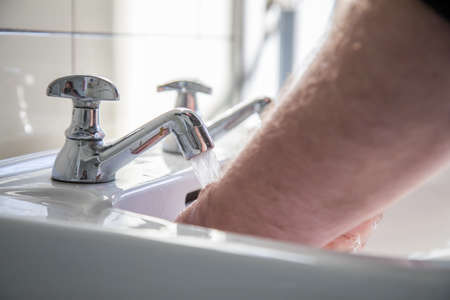 Man using washbasin with tap water for washing hands