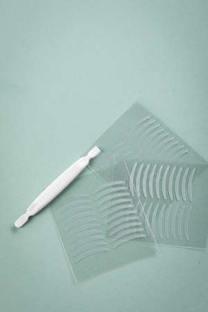 Artificial eyelid crease double tapes for hooded eyes on pastel mint green background