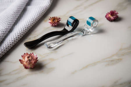 Derma roller for anti ageing lifting cosmetic treatment in cosmetologist beauty salon with marble background and dried blossomsの写真素材