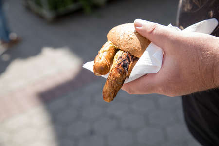 Man eating a couple of grilled Bavarian Bayreuth Bratwurst pork sausage with mustard in wheat bread...