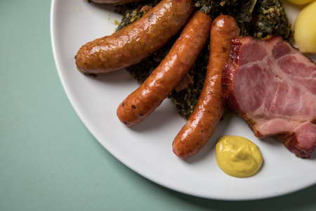 Oldenburger green cabbage with sausage mix, Kassler pork neck, boiled potatoes and mustard is an traditional German winter dishの写真素材