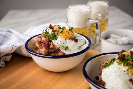 North German Hamburg Labskaus is a delicacy with corned beef, potatoes, beetroot, pickled gherkins, fried egg, herring and beer on marble tableの写真素材