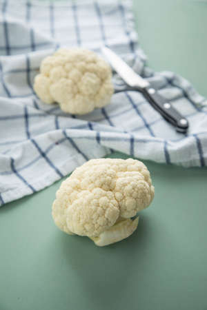 White cauliflower on kitchen towel with knife on pastel green backgroundの写真素材