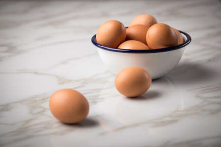 Brown chicken eggs in enamel bowl on marble backgroundの写真素材