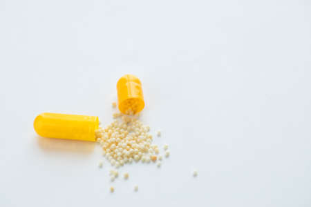 Yellow pill capsule with ingredients on white backgroundの写真素材