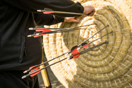Male archer pulling arrows from archery leisure time hobby outdoor shooting out of straw target diskの写真素材