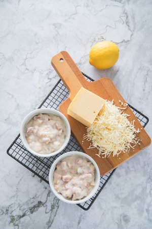 Traditional Eastern Germany DDR GDR cuisine -WÃ¼rzfleisch Ragout Fin a pork and poultry meat meal in light roux sauce with shredded Gouda cheese with lemon on cooling grid and light marble backgroundの写真素材