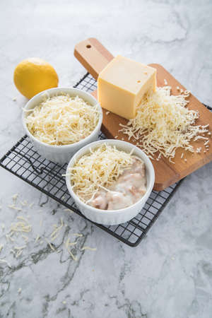 Traditional Eastern Germany DDR GDR cuisine -WÃ¼rzfleisch Ragout Fin a pork and poultry meat meal in light roux sauce with shredded Gouda cheese with lemon on cooling grid and light marble backgroundの写真素材