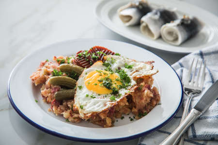 North German Hamburg Labskaus is a delicacy with corned beef, potatoes, beetroot, pickled gherkins, fried egg and herring on enamel plateの写真素材