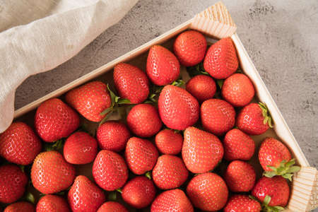 Fresh strawberries in wood tray from farmers market on linen towel and light marble backgroundの写真素材