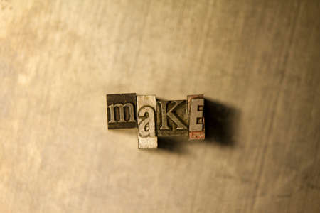Bronze metal "Make" typography lettering on wooden backgroundの写真素材
