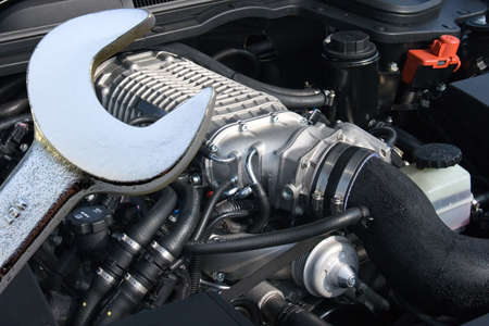 Spanner with V8 supercharged car engine in the background