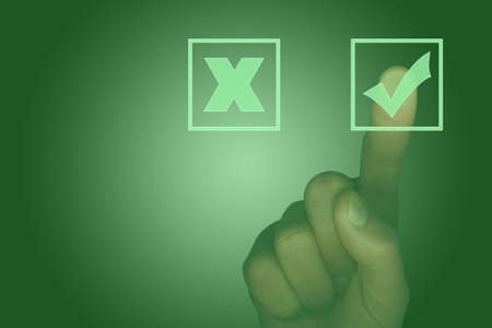 Computer touch screen with tick box, cross box and finger selecting the tick