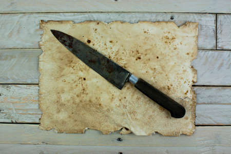 Piece of old paper and a knife on wooden planksの写真素材