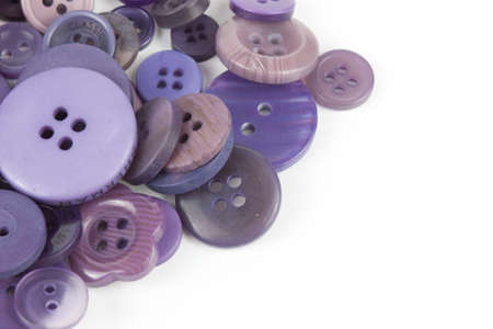 Close up of various purple button scattered on a white surface.の写真素材
